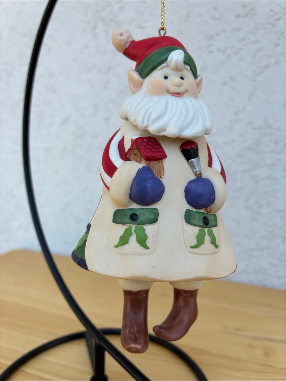 Ceramic elf painting a bird house bell ornament with little floppy legs